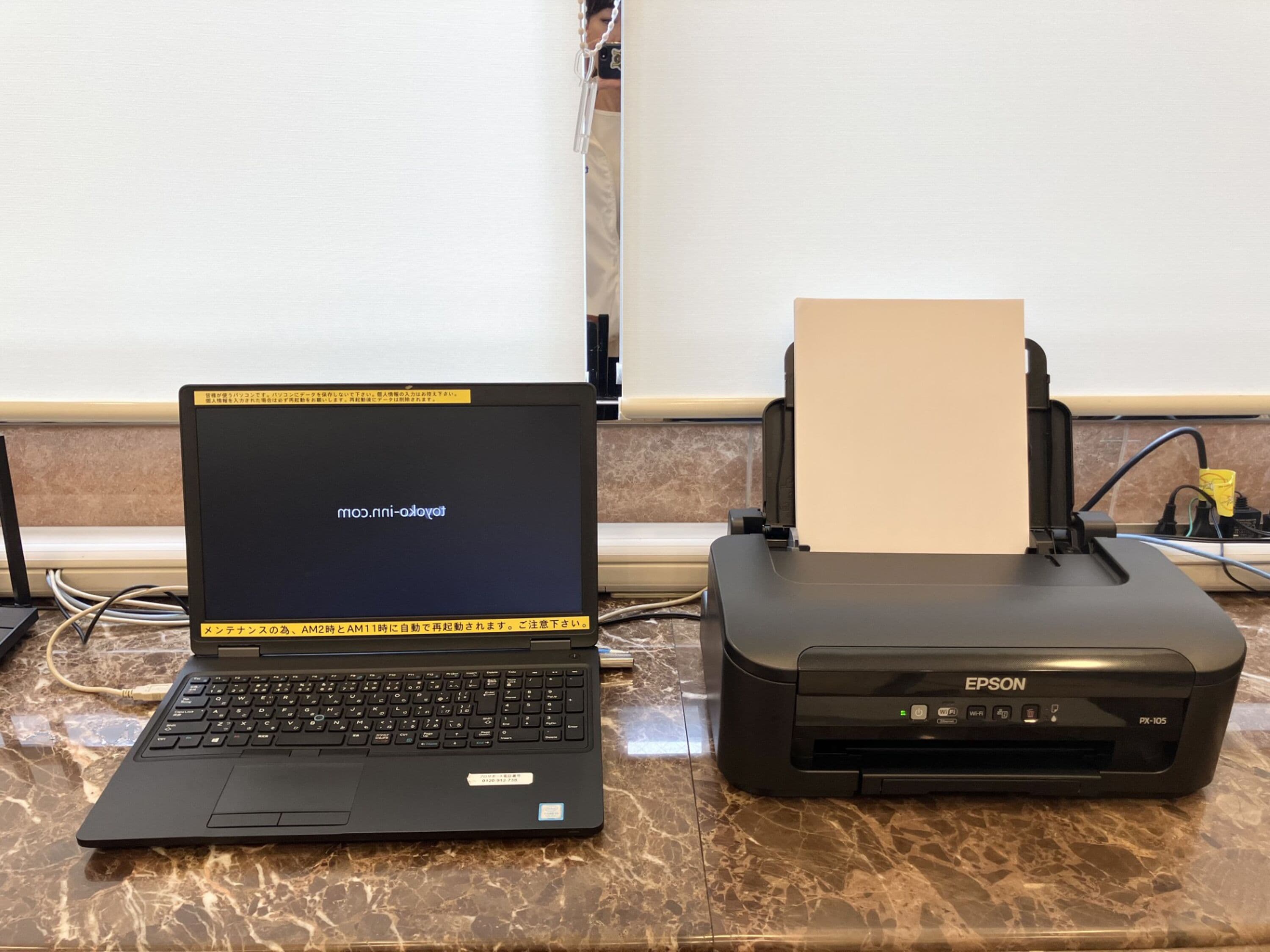 Ein Laptop und ein Epson-Drucker auf einer Marmorarbeitsplatte.
