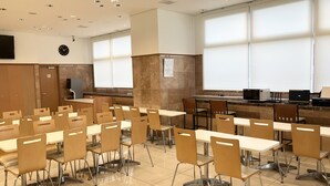 A classroom with beige chairs and tables, a clock on the wall, and a projector screen. - Toyoko Inn Matsue Ekimae (Matsue)