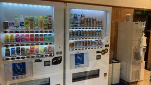 Máquinas expendedoras con bebidas y aperitivos, un dispensador de agua y un cartel de Toyoko Inn.
