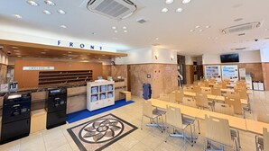 A modern hotel lobby with a reception desk, a 'FRONT' sign, a patterned floor design, and a seating area with tables and chairs. - Toyoko Inn Miyazaki Ekimae (Miyazaki)