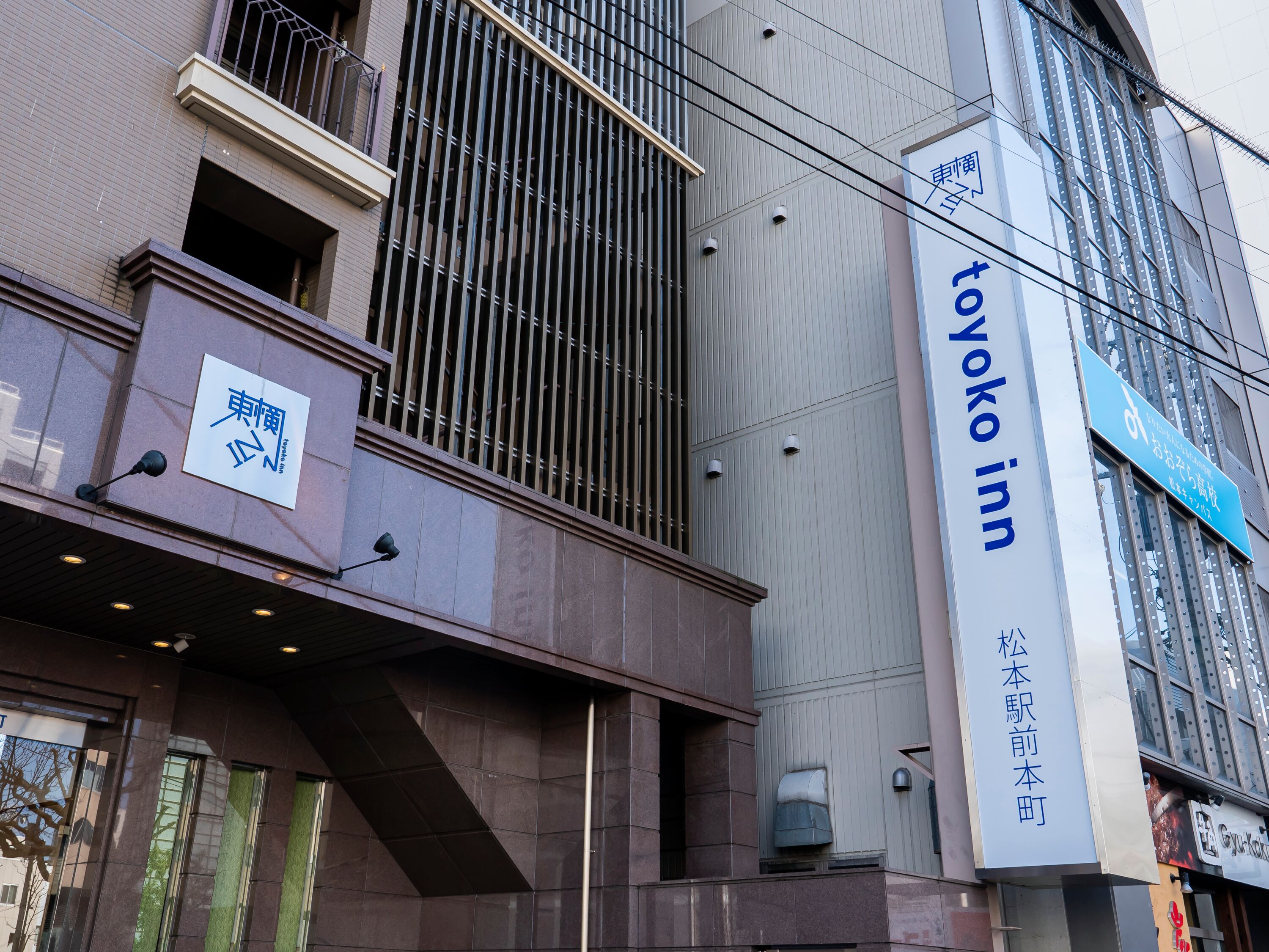 A building with a sign for 'Toyoko Inn' and another sign with Japanese characters.