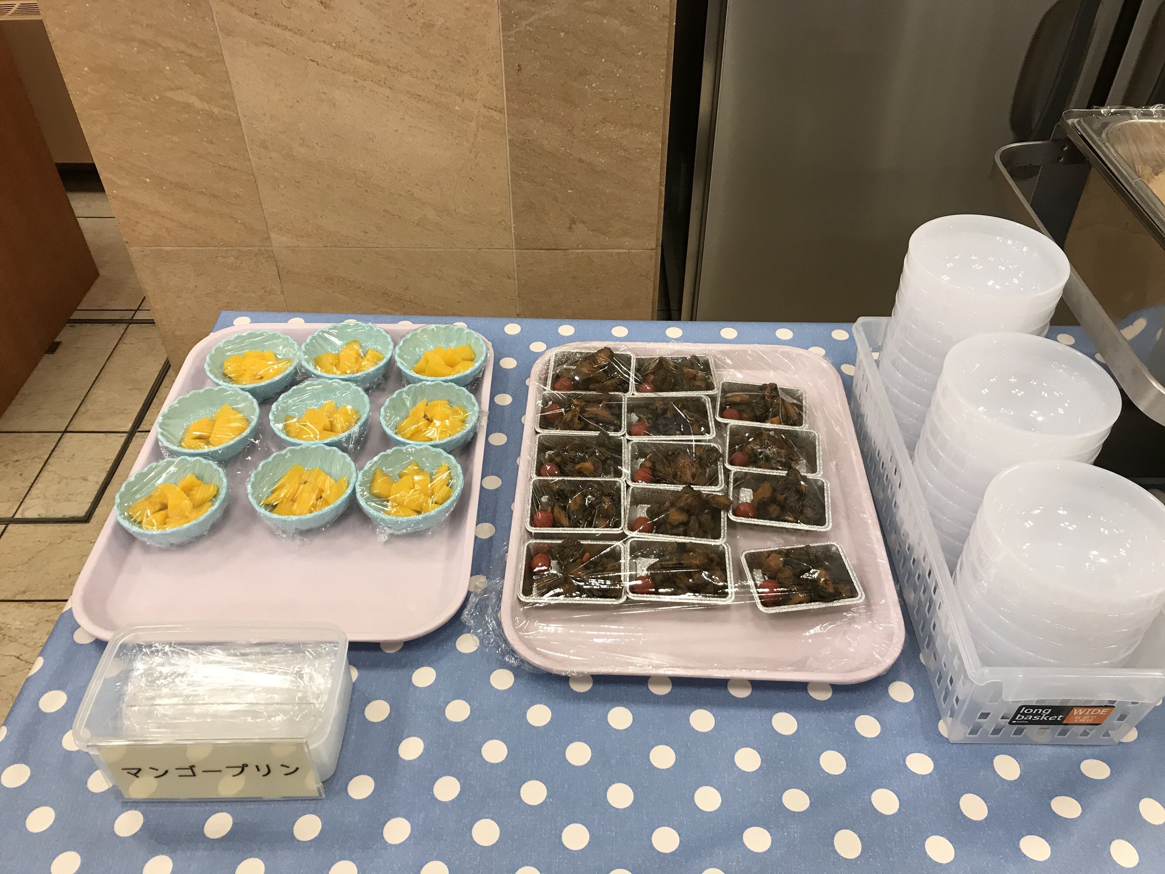 Une table avec des aliments, des récipients en plastique et une nappe à pois.