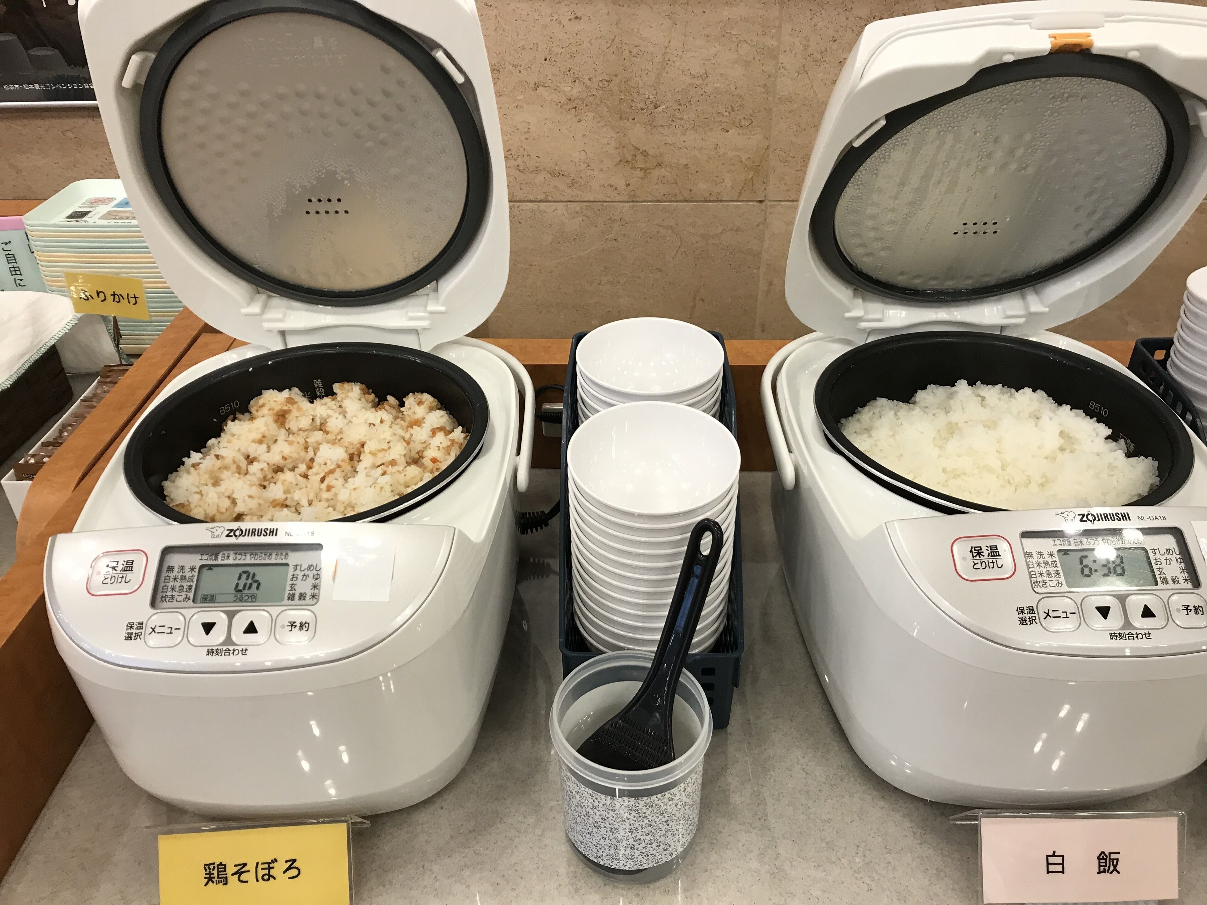 Two rice cookers with lids open, displaying cooked rice inside.