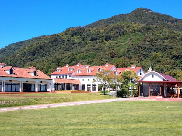 A row of white buildings with red roofs, set against a backdrop of a green hill. - Toyoko Inn Izumo-shi Ekimae (Izumo)