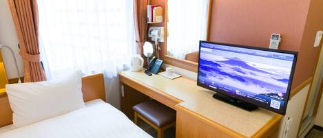 A hotel room with a bed, desk, and a television displaying a landscape.