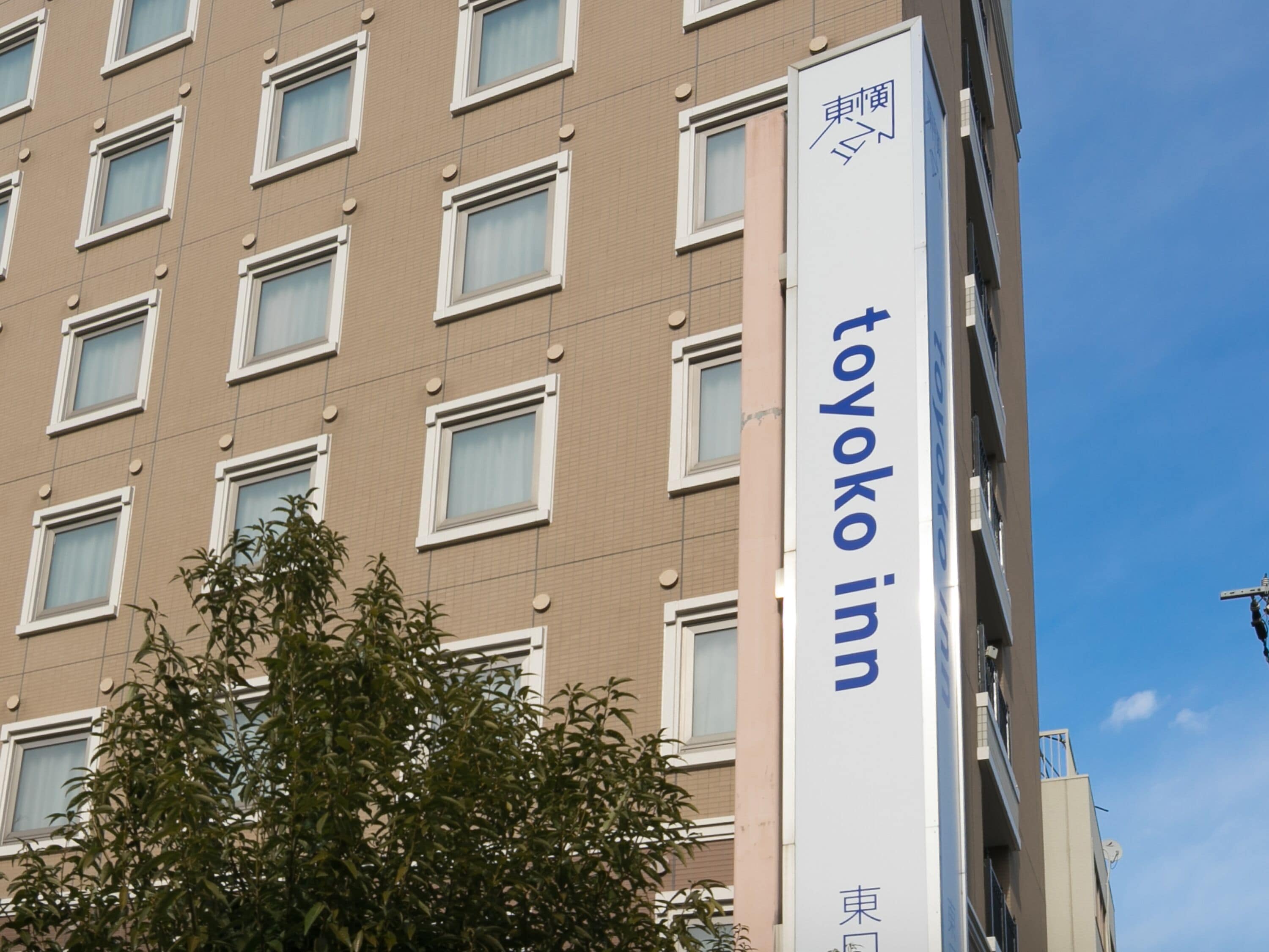 A building with a sign reading "Toyoko Inn" and multiple windows.