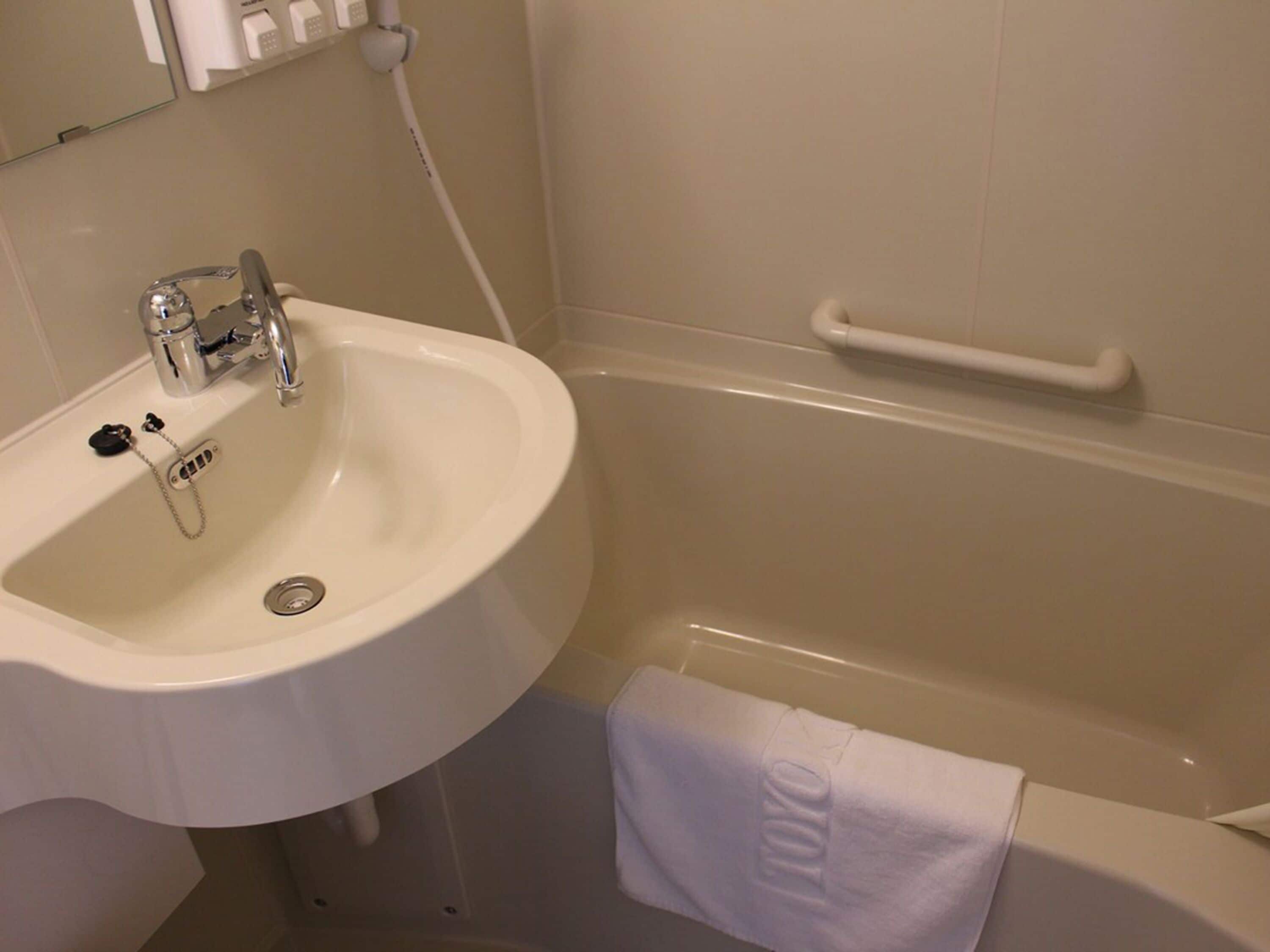 Kylpyhuone, jossa on valkoinen pesuallas, peili ja kylpyamme.
