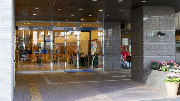 The entrance of a building with a glass door, a tiled floor, and a potted plant. - Toyoko Inn Kawasaki Station Shiyakusho Dori (Kawasaki)