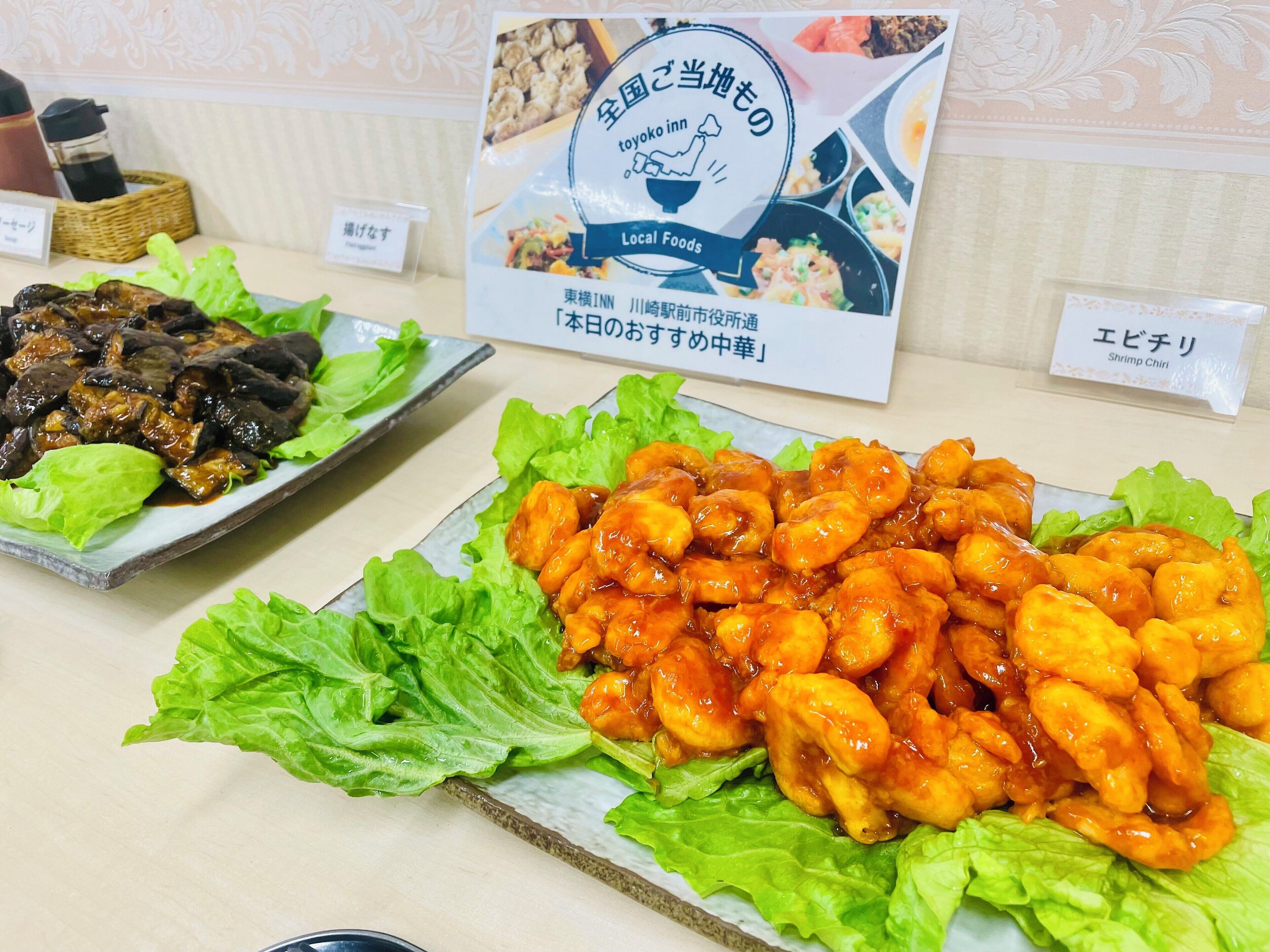 Una mesa de buffet con varios platos, incluyendo un plato de alitas de pollo glaseadas y un guiso de pescado a la parrilla, ambos servidos sobre lechuga.
