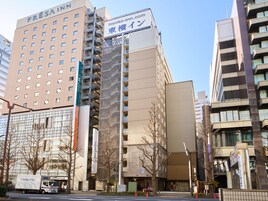 Un edificio de varios pisos con un letrero que dice 'Fresain Inn' y 'toyoko-inn.com'.