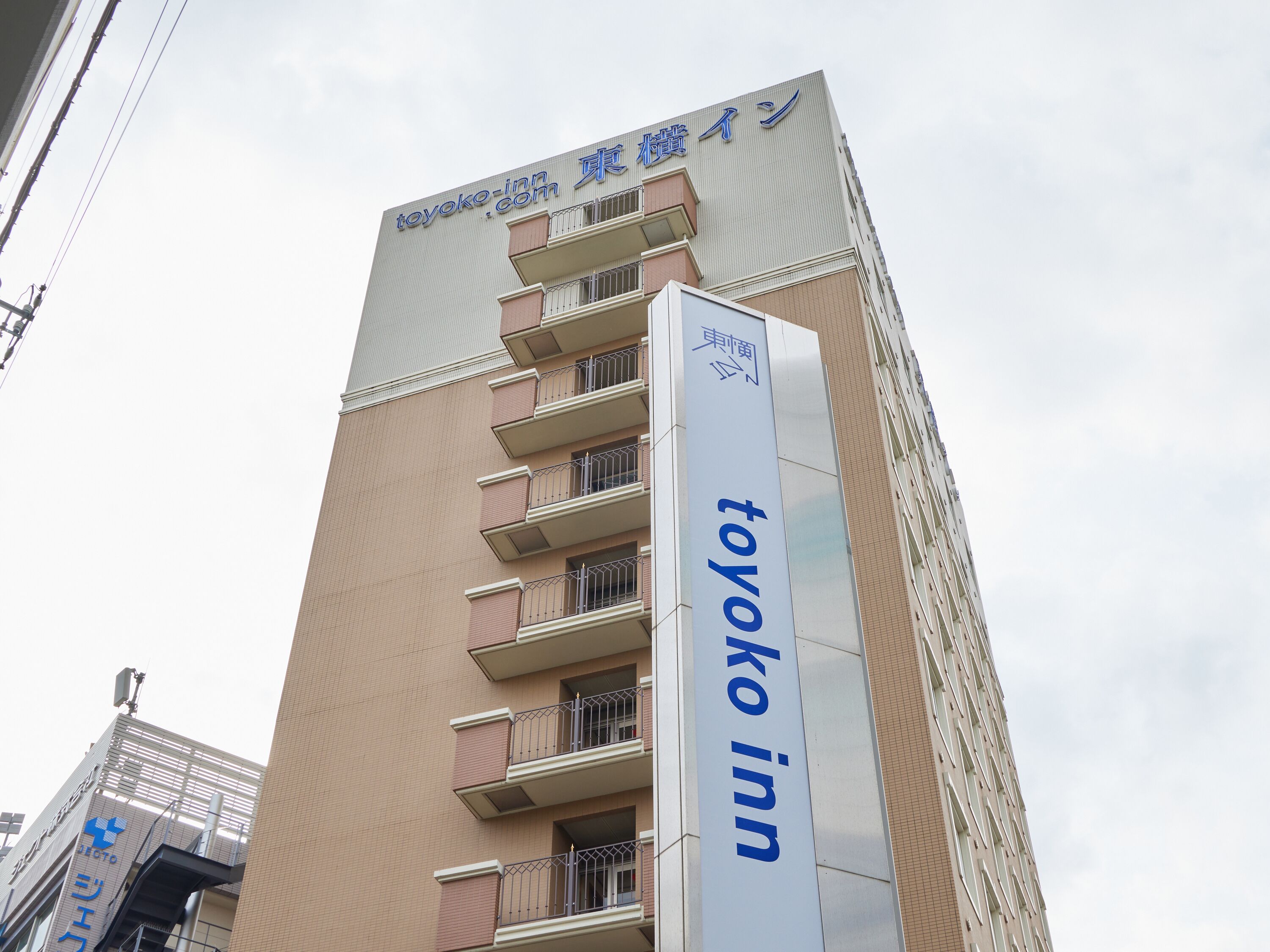 Un edificio alto con un letrero que dice "toyoko inn" y una dirección web "toyoko.com".