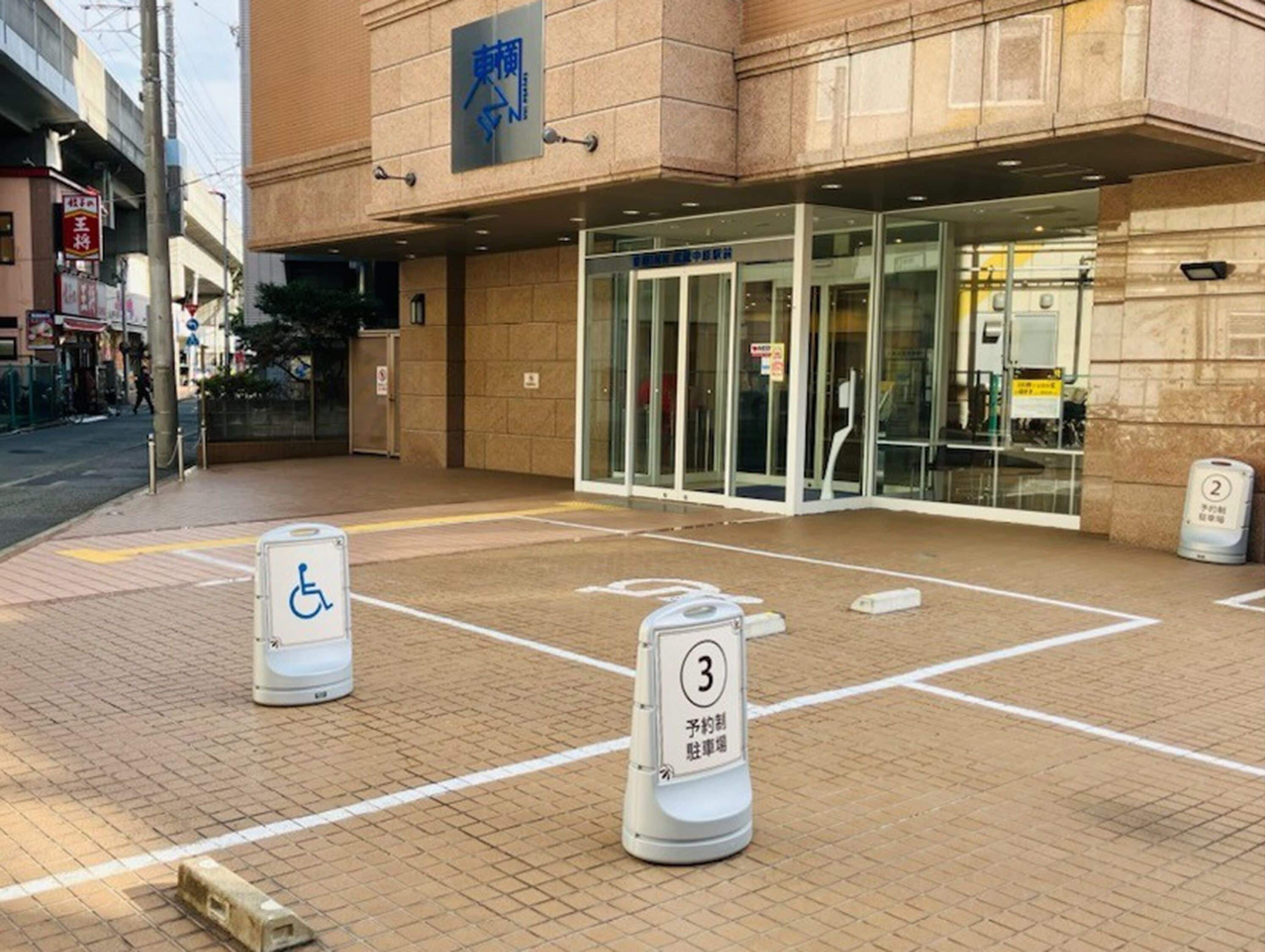 A hotel entrance with a wheelchair-accessible ramp and numbered parking spaces.