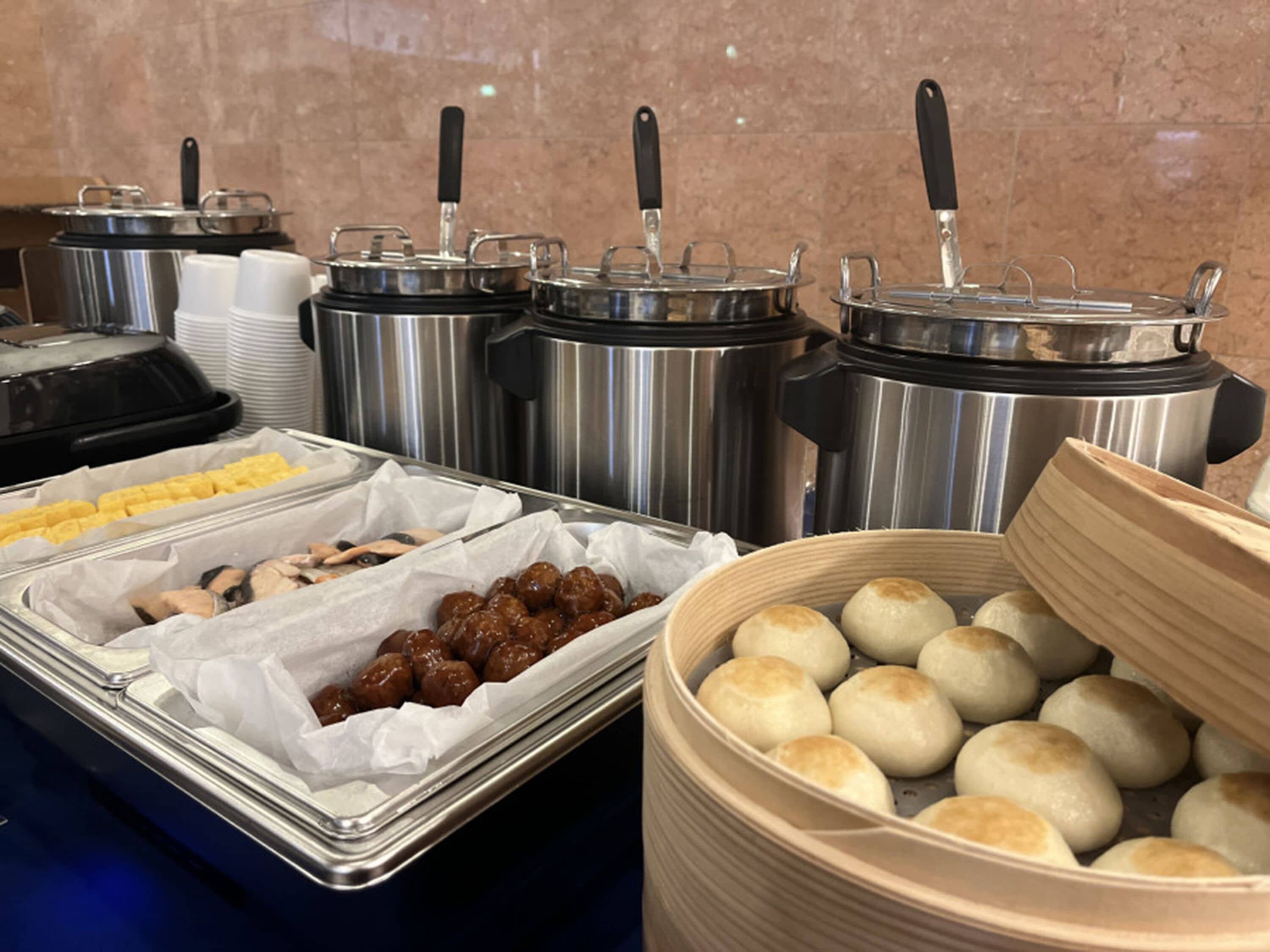 Un bufé con diferentes opciones de comida, incluyendo albóndigas, dumplings y una bandeja de pasteles.