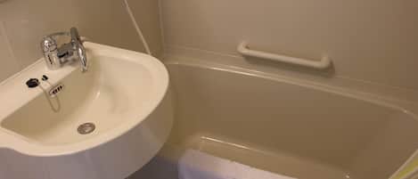 Un baño con un lavamanos blanco, una bañera y una toalla colgada en la pared.