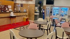 Een hotel lobby met een receptiebalie, automaten en zithoeken.