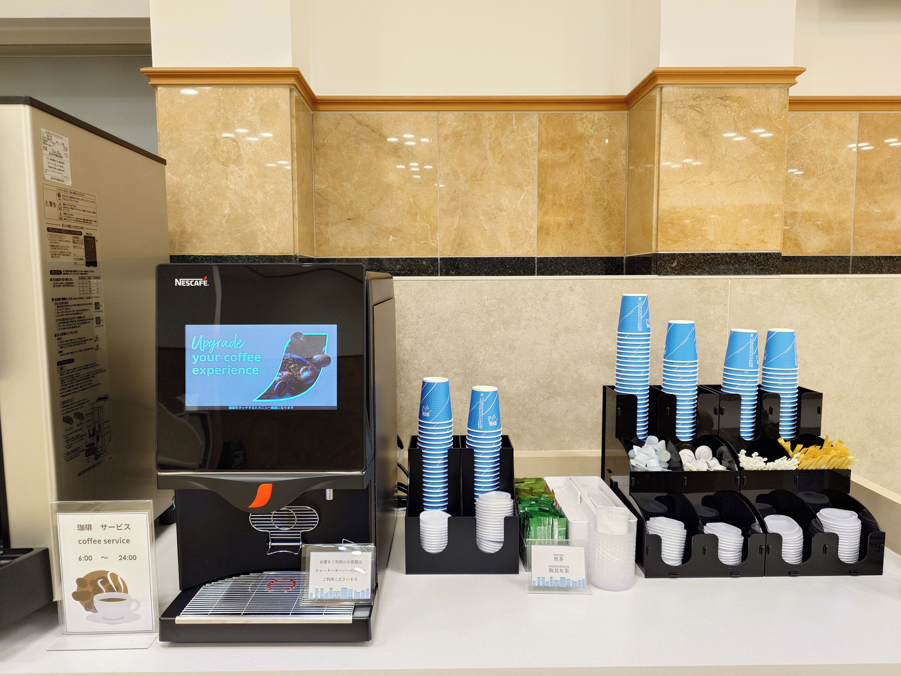 A coffee service area with a Nescafé machine, disposable cups, and a menu board.
