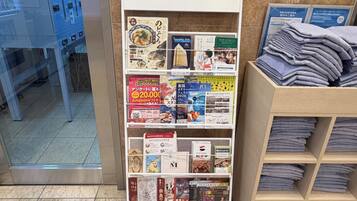 A bookstore with a variety of books and magazines, a display of folded towels, and a blue cabinet in the background.