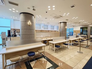 A modern indoor space with multiple seating areas, a coffee machine, and a counter. - Toyoko Inn Niigata Ekimae (Niigata)