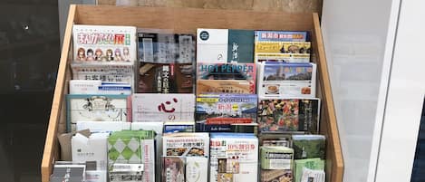 A wooden display case filled with various books and magazines, including titles like 'Alice in Wonderland' and 'Yogurt'.