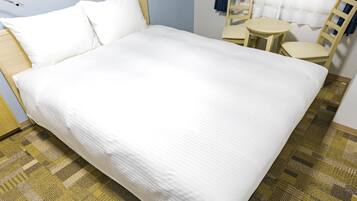 Una cama bien hecha con sábanas blancas en una habitación con alfombra estampada.