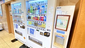 Automaten mit verschiedenen Getränken und Snacks, ein Toshiba-Kühlschrank und ein gerahmtes Schild auf der rechten Seite.