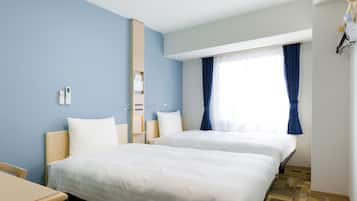 Habitación de hotel con dos camas, un escritorio, un espejo y una ventana con cortinas.