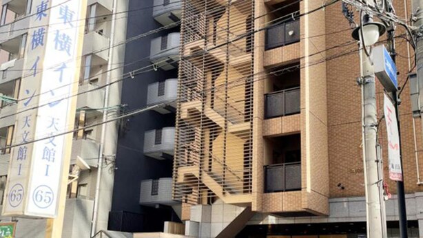 A multi-story building with a modern architectural design, featuring a prominent staircase and a ground-level entrance with a glass facade. - Toyoko Inn Kagoshima Temmonkan No.1 (Kagoshima)