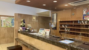 A hotel reception area with a marble counter, a map, a clock, and a shelf with papers. - Toyoko Inn Kagoshima Temmonkan No.1 (Kagoshima)