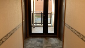 A hotel entrance with a double door, a green emergency exit sign, a metal gate, and a carpeted floor. - Toyoko Inn Kagoshima Temmonkan No.1 (Kagoshima)
