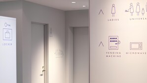 A modern hallway with minimalist decor, including a wall-mounted sign with icons for a locker, a vending machine, and a microwave. - Toyoko Inn Tokyo Haneda Kuko No.2 (Tokyo)