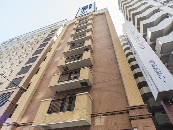 Un hôtel à plusieurs étages, doté d’une façade beige, de nombreux balcons et d’une enseigne bien visible indiquant « Toyoko Inn ».