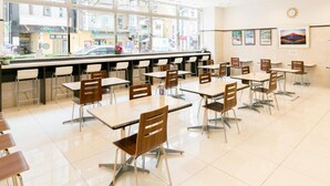 A spacious indoor dining area with multiple tables and chairs, large windows offering a view of the street outside, and a clean, modern design. - Toyoko Inn Fukushima-eki Higashi-guchi No.1 (Fukushima)