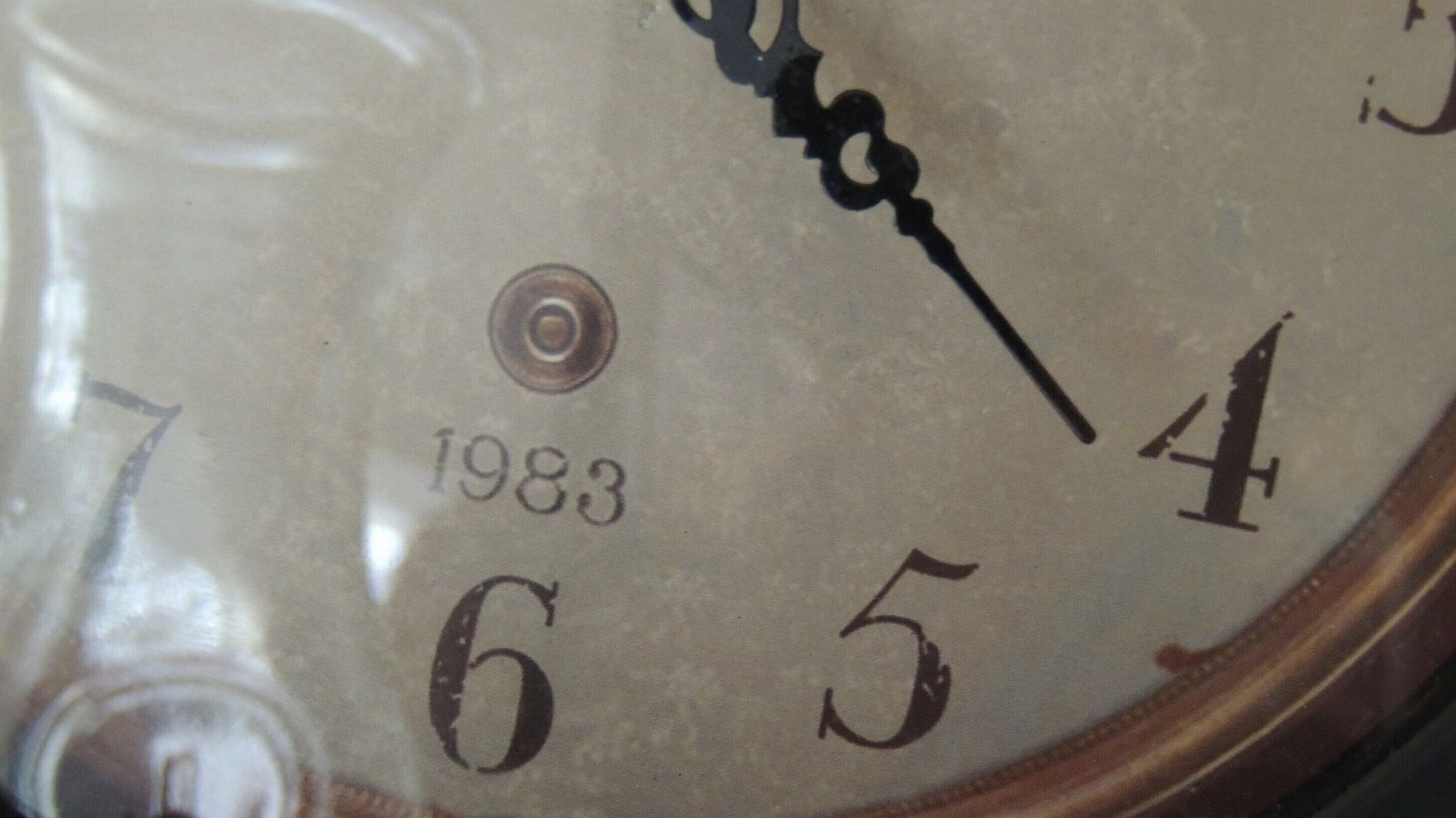 A close-up of a clock face with the year 1983 visible.