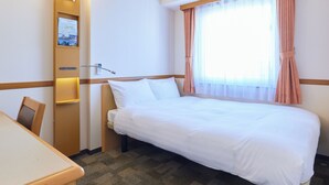 A hotel room with a bed, a desk, a chair, a wall-mounted lamp, and a window with curtains. - Toyoko Inn Kofu Station Minami 1 (Kofu)
