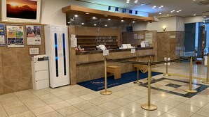 A reception area with a marble floor, a reception desk, a framed picture on the wall, and a blue mat with the hotel's logo. - Toyoko Inn Yokohama Stadium Mae No.2 (Yokohama)