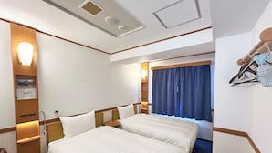 Een hotelkamer met twee bedden, een bureau, een stoel en een raam met gordijnen.
