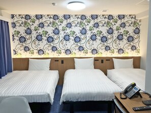 Ein Hotelzimmer mit zwei Betten, einem Schreibtisch mit Telefon und floralem Wandpapier.