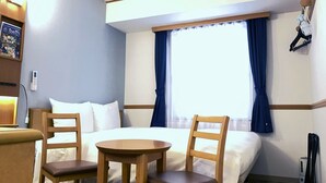 A hotel room with a bed, two chairs, a small table, a window with curtains, a coat rack, and a wall-mounted TV. - Toyoko Inn Kumamoto Sakuramachi Bus Terminal Mae (Kumamoto)