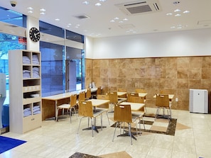 A modern indoor space with tables and chairs, a clock, and a large window. - Toyoko Inn Kumamoto Sakuramachi Bus Terminal Mae (Kumamoto)