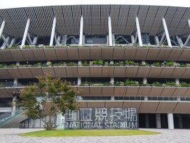 A modern stadium with multiple levels of seating and a prominent sign reading "NATIONAL STADIUM".