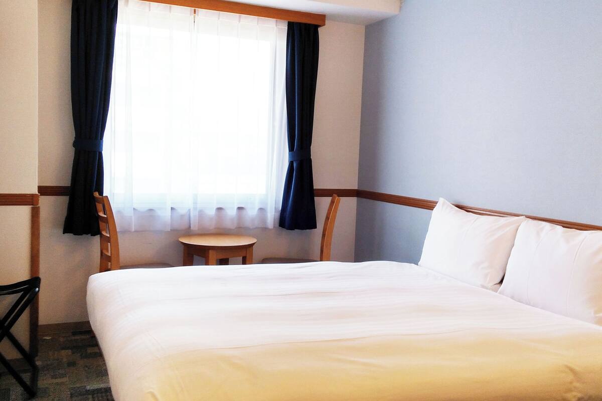 Ein Hotelzimmer mit einem Bett, einem kleinen Tisch und einem Stuhl.