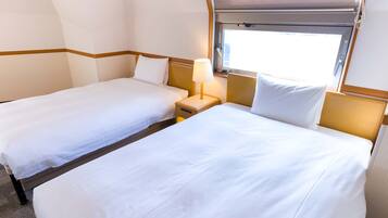 A hotel room with two beds, a window, and a lamp.