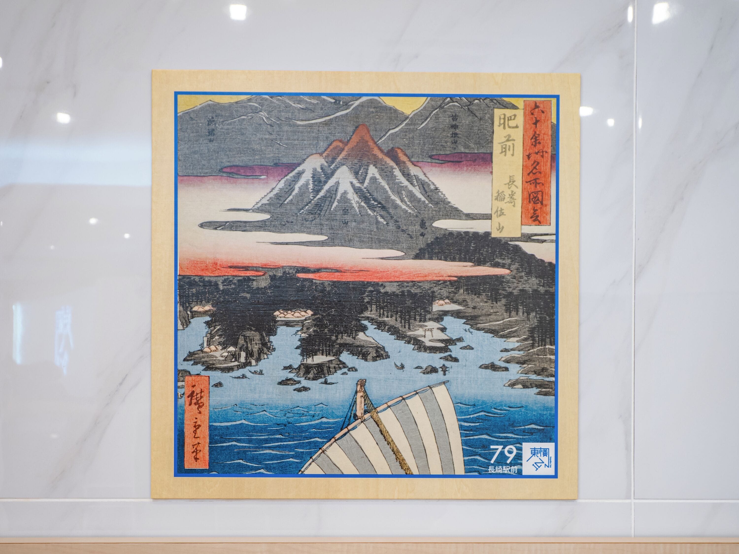 A framed Japanese artwork depicting a mountain, a body of water, and a sailboat.
