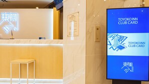 A reception area with a marble floor, a reception desk, a standing desk, and a digital display advertising the Toyota Inn Club Card. - Toyoko Inn Nagasaki Ekimae (Nagasaki)