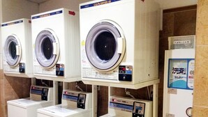 A row of coin-operated washing machines in a public facility.