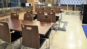 A dining area with multiple tables and chairs, a microwave, and lockers in the background. - Toyoko Inn Tokyo Korakuen Bunkyokuyakusho Mae (Tokyo)