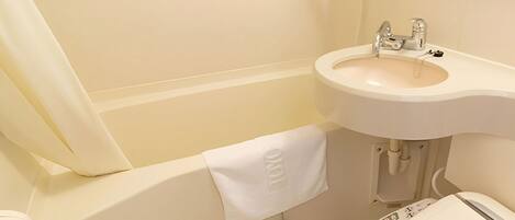 Une salle de bain avec un lavabo blanc, des toilettes et une baignoire.