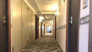 Un pasillo de hotel con piso alfombrado, puertas a ambos lados y una lámpara en el techo.