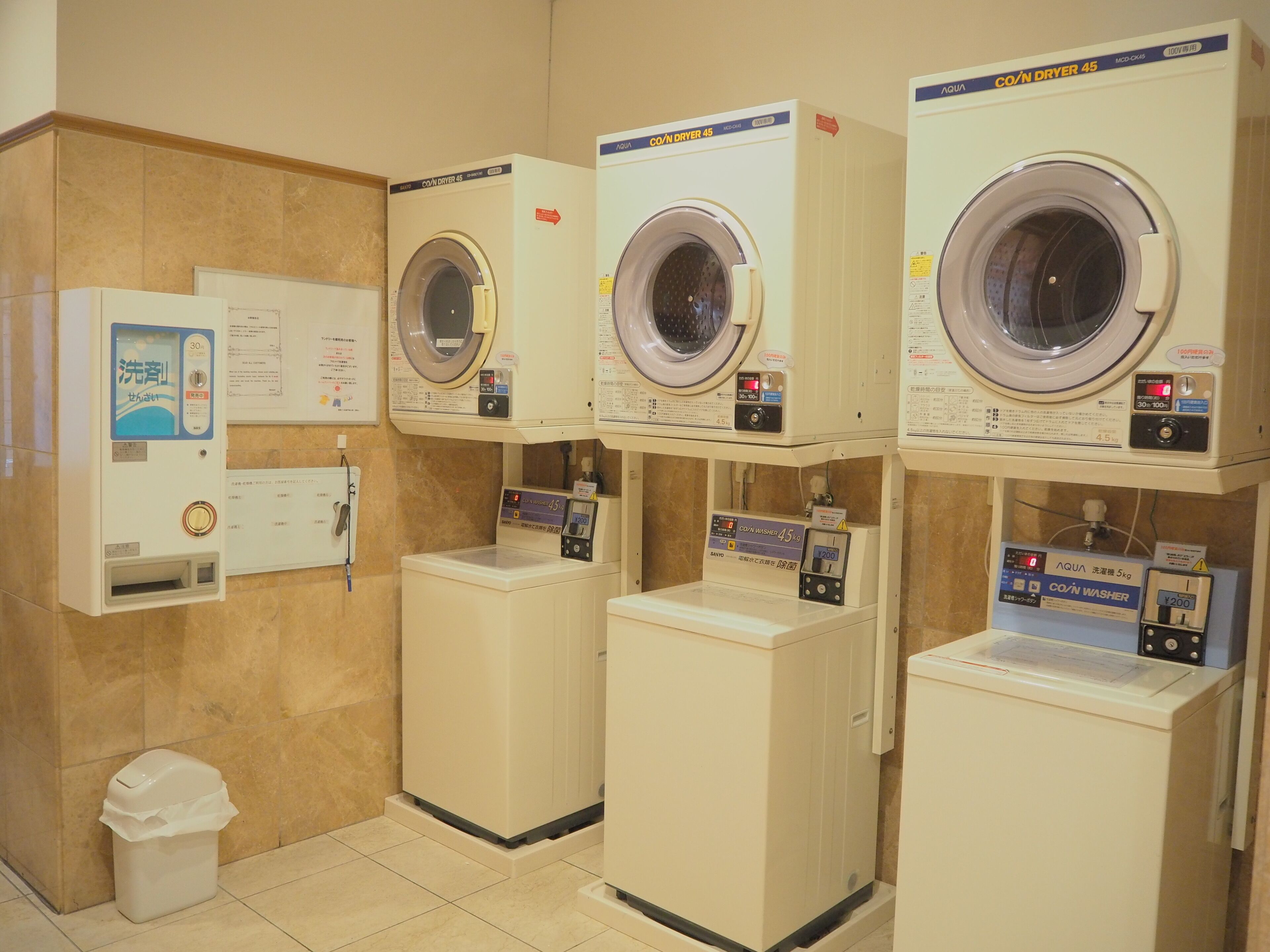 A laundry facility with multiple washing machines and a coin-operated washing machine.