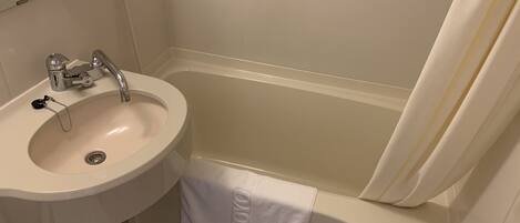 A bathroom with a sink, mirror, and bathtub.